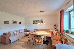 A cozy living room with a sofa, chairs, a dining table, and a window with curtains. - Siegfried Heim||Pankrazberg (Pankrazberg)