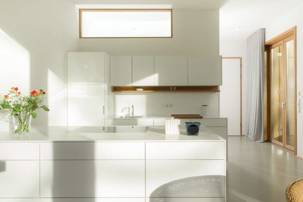 A modern kitchen with white cabinetry, a built-in oven, and a window above the sink.