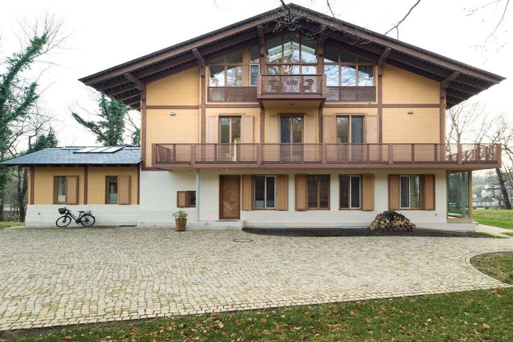 A two-story building with a balcony, a bicycle parked outside, and a pile of firewood.