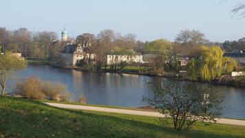 A riverside view with a park, a building with a green dome, and a pathway.