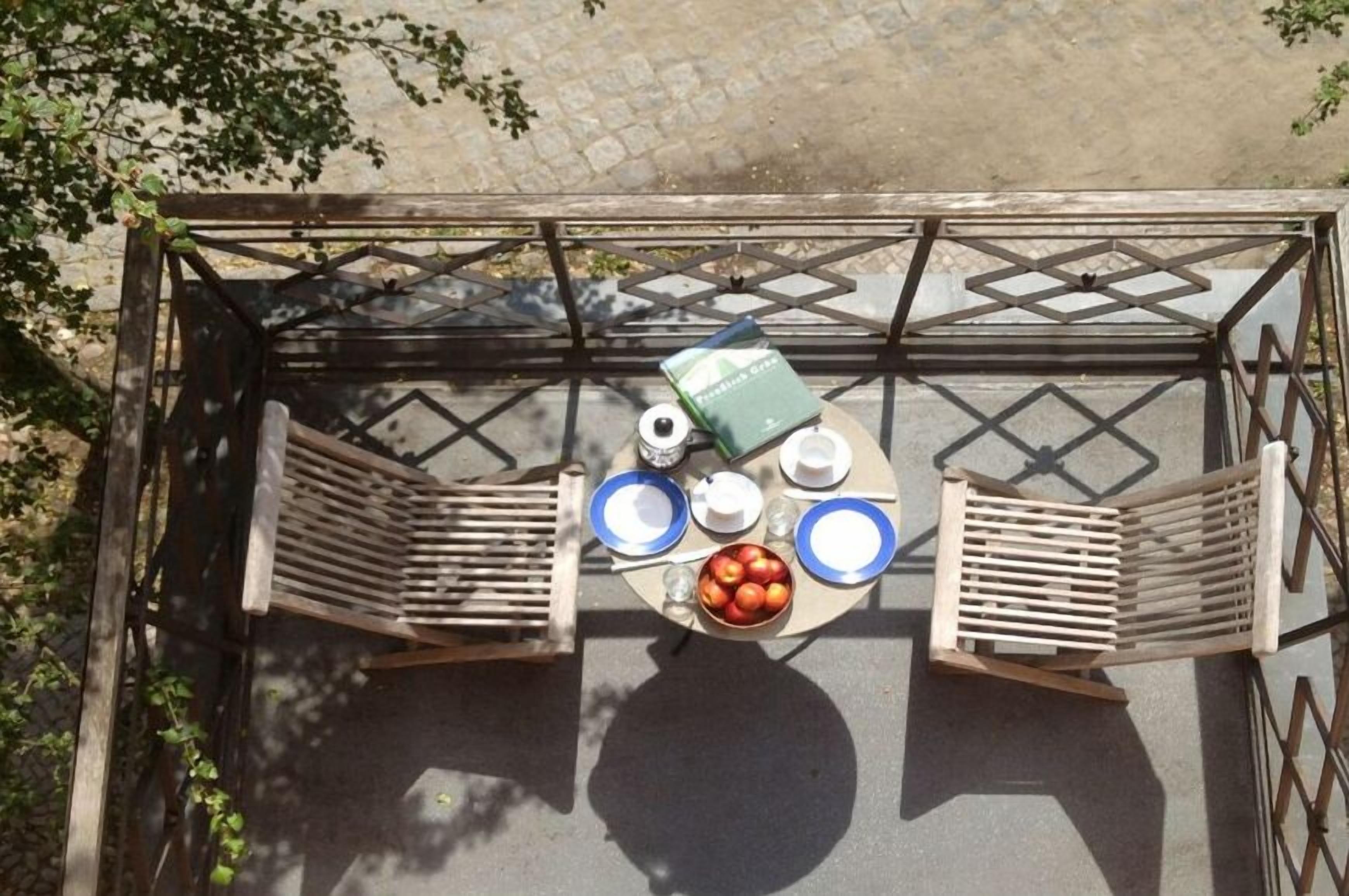 An outdoor seating area with a table, chairs, and a bowl of fruit.