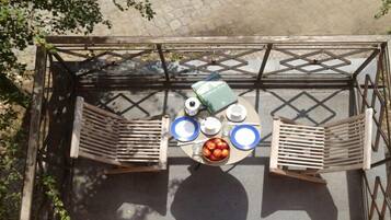 An outdoor seating area with a table, chairs, and a bowl of fruit.