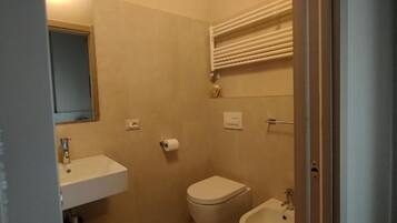 A small bathroom with a toilet, bidet, and sink.