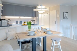 A modern kitchen with grey cabinets, a central island with seating, and a pendant light. - Friesenkoje in Mellhörn (List)