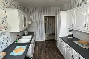 Eine Küche mit weißen Schränken, einer schwarzen Arbeitsplatte und einer ornamental gestalteten Spritzschutzwand.