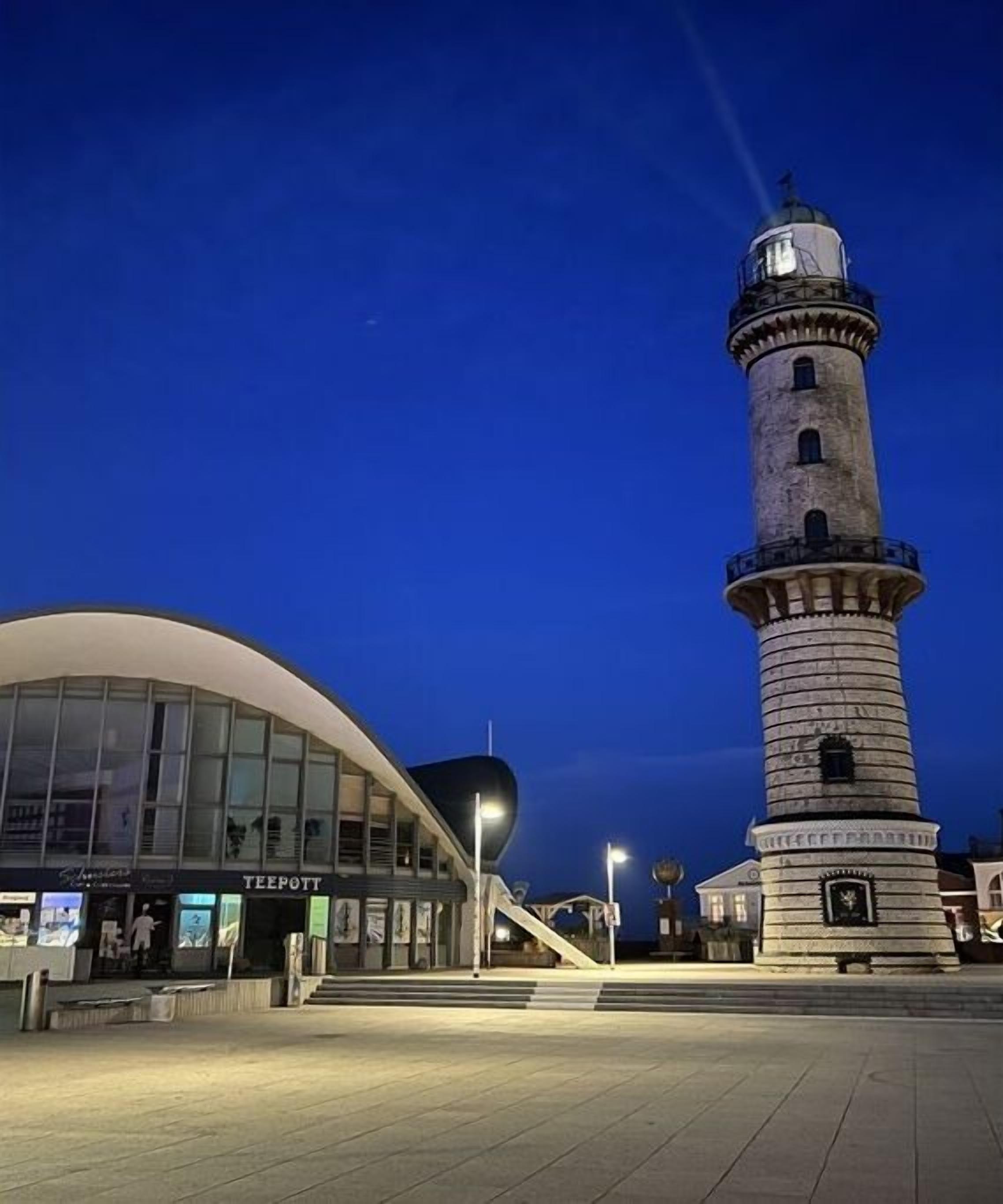 Un phare avec un bâtiment moderne attenant.
