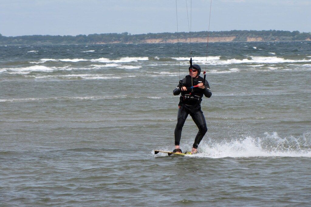 Uma pessoa praticando windsurf em um corpo d'água com ondas.