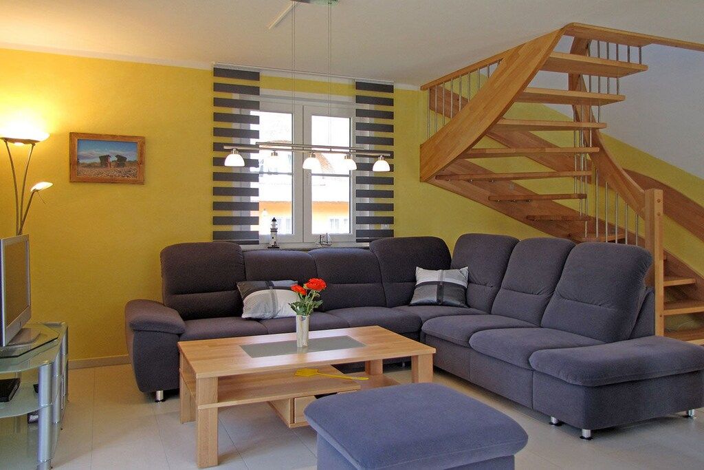 A living room with a sofa, a coffee table, a TV, and a staircase.