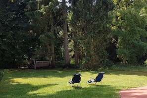A grassy area with two blue lawn chairs and a wooden bench. - Eldenholz on the Reeck Canal (Waren)