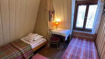 Ein Zimmer mit zwei Holzbetten, einem kleinen Tisch, einem Stuhl und einem Fenster.