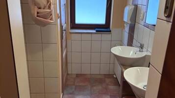A narrow bathroom with two sinks, a window, and a towel rack.