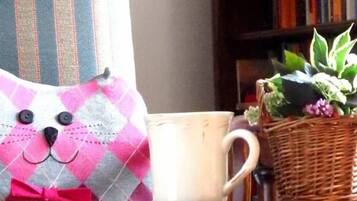 Un fauteuil à rayures, un coussin, une tasse et un panier en osier contenant une plante, le tout posé sur une table en bois.