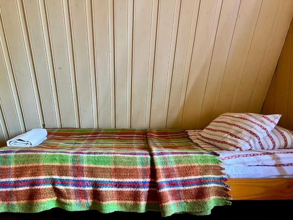 Un lit simple avec une couverture à rayures et un oreiller à motifs.