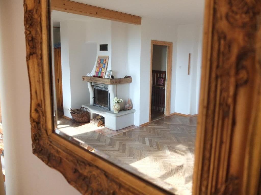 A room with a fireplace, a mirror, and a herringbone floor pattern.