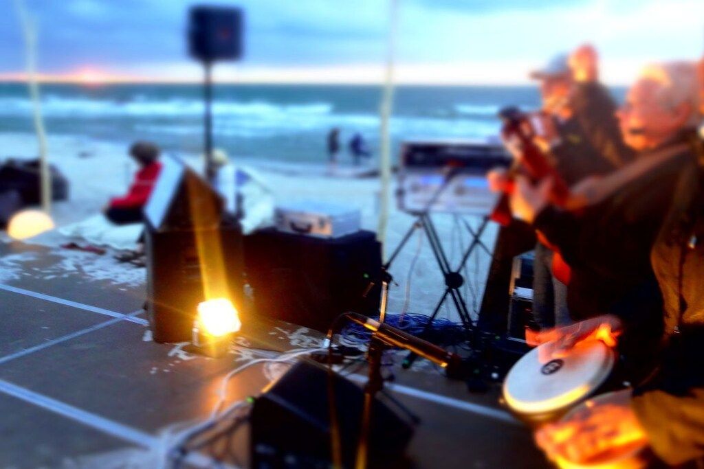 Un evento en la playa con equipo musical y un altavoz sobre la arena.