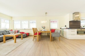 A modern living room with a sofa, a dining table, and a kitchen area. - Holiday home in Zingst with swimming pool (Zingst)