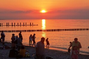 A beach scene with people, a sunset, and a pier. - Holiday home in Zingst with swimming pool (Zingst)