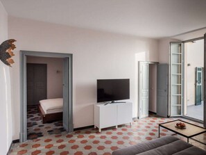 A compact living space with a television, a sofa, and a small table. - Holiday Apartment With 1 Bedroom (Diano Castello)
