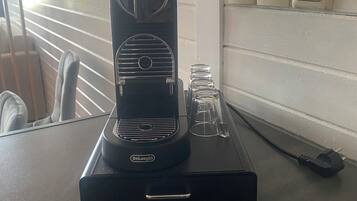 A DeLonghi espresso machine on a table with a window in the background.