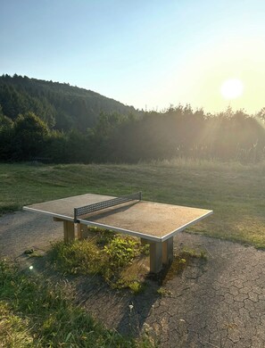 A ping pong table in an outdoor setting with a clear sky and sunlight.