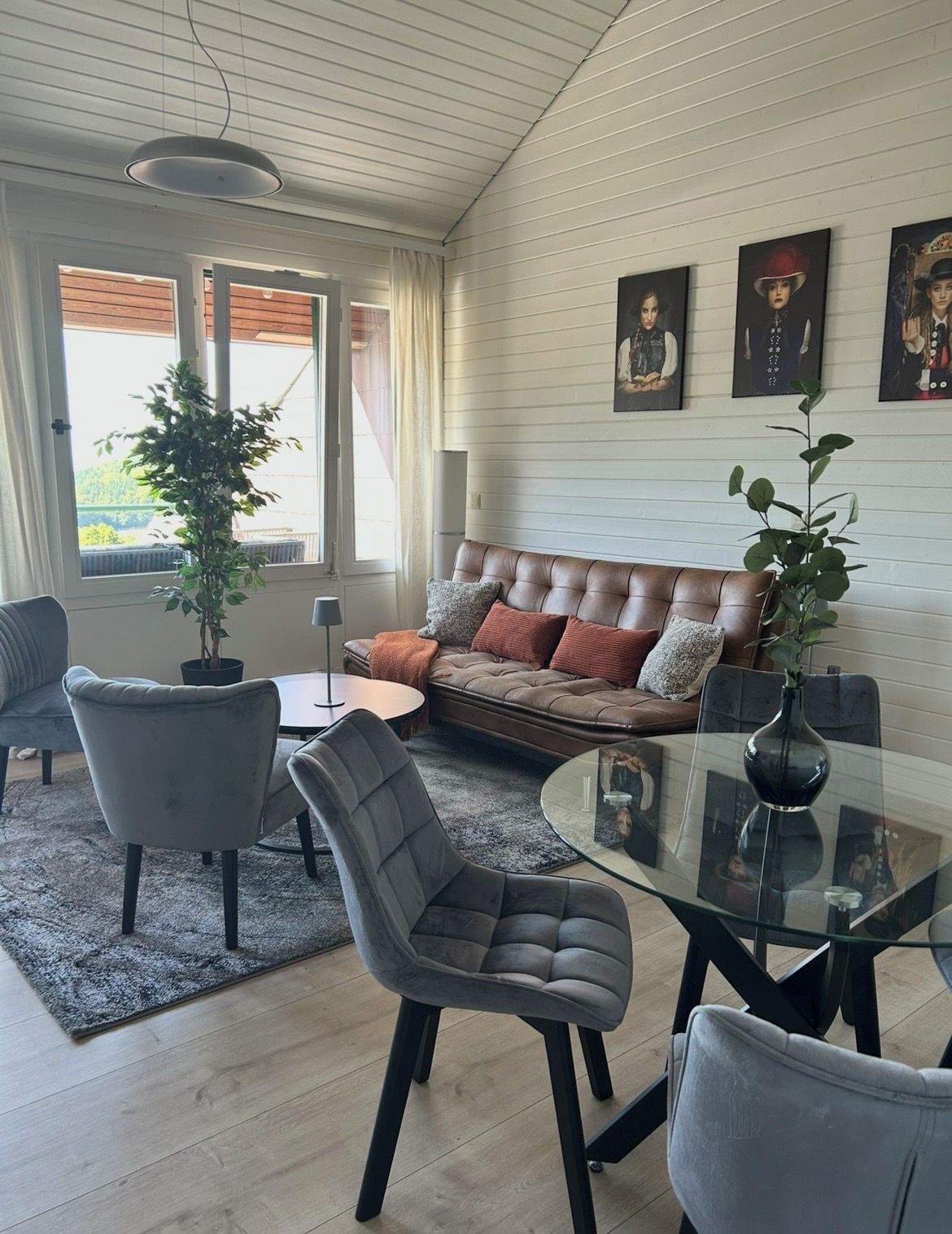 Ein modernes Wohnzimmer mit einer Ledersofa, einem Glastisch und einem Blumentopf.