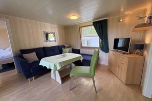 A room with a sofa, a dining table, a chair, a television, and a cabinet. - Bungalow in Koserow with swimming pool (Koserow)