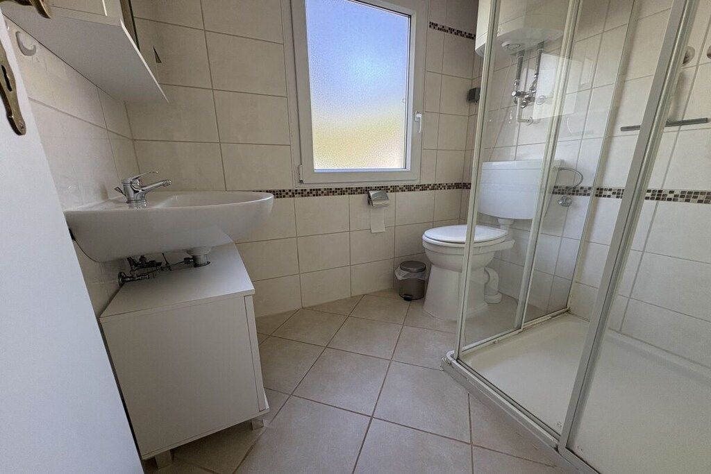 Un baño con cabina de ducha de vidrio, un lavamanos y un inodoro.