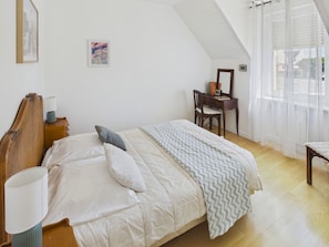 A bedroom with a bed, a desk, a chair, and a window with curtains. - Near the sea, house & garden – 4 adults/1 child (Penmarch)
