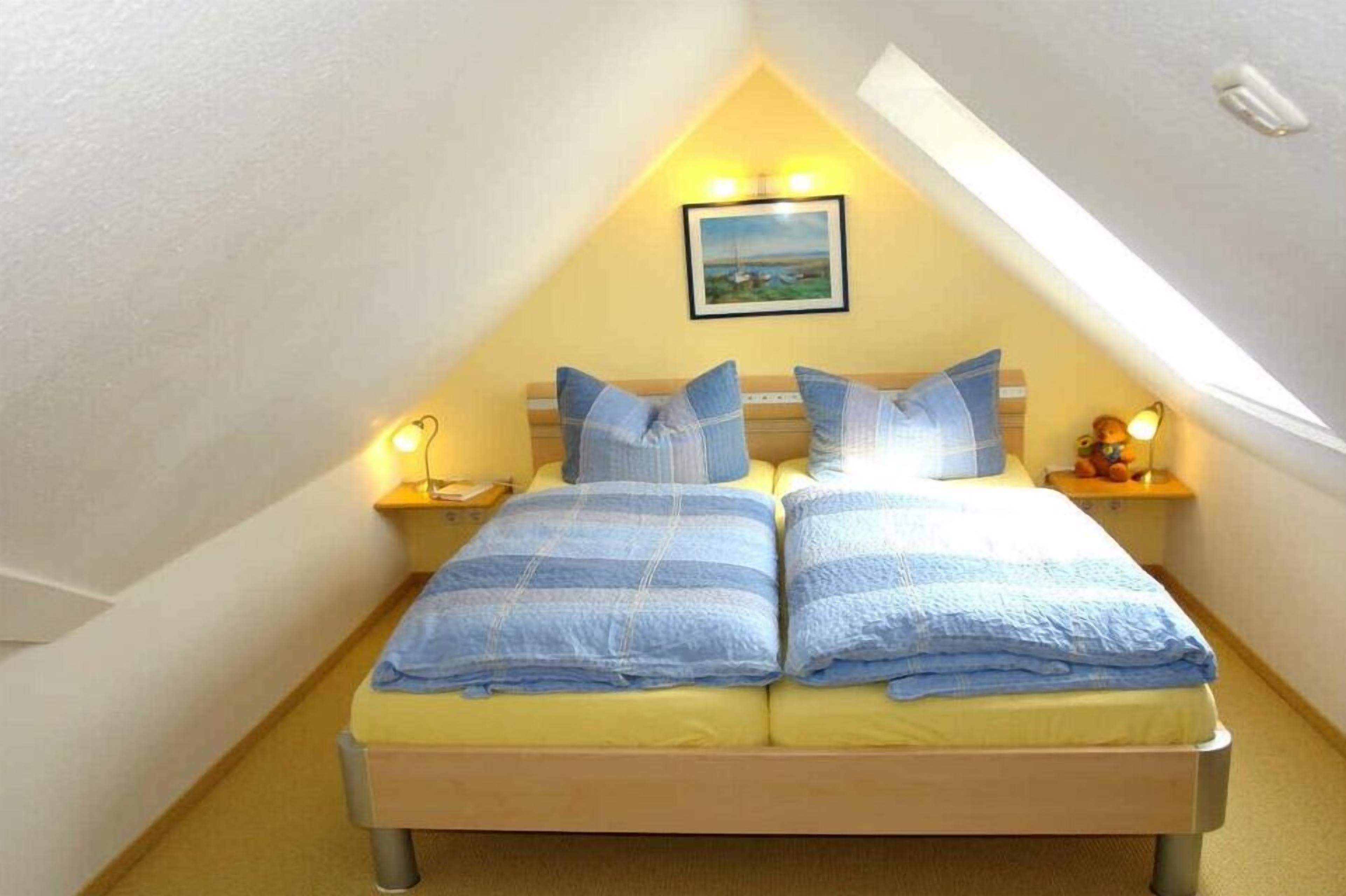 A twin bed with a headboard, two bedside tables with lamps, and a framed picture on the wall.