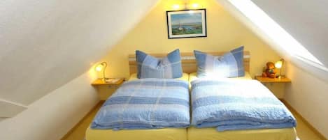 A twin bed with a headboard, two bedside tables with lamps, and a framed picture on the wall.