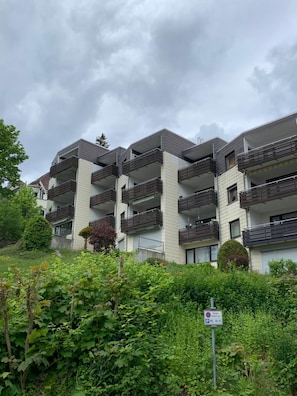 Ein mehrstöckiges Wohngebäude mit Balkonen, umgeben von viel Grün.