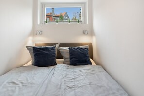 A bedroom with a single bed, two pillows, a window, and a view of buildings outside. - Apartment 'Harz 21' with Dreamy Balcony Views (Braunlage)