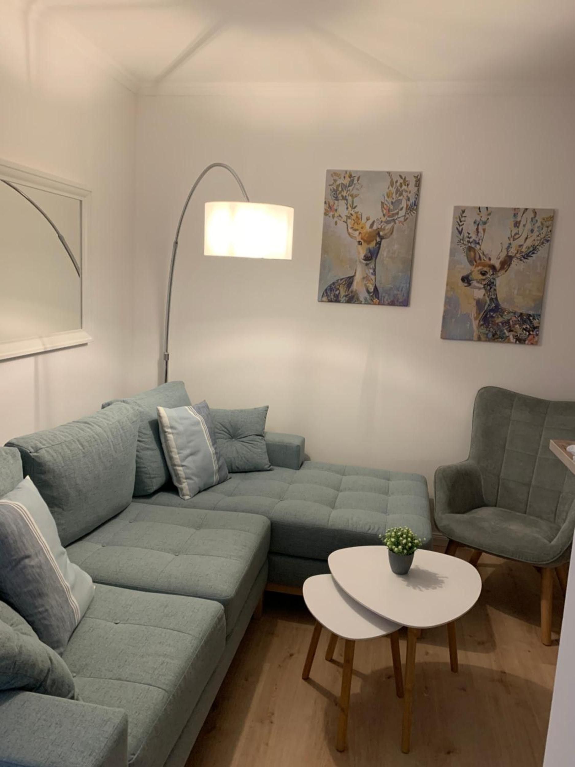 A modern living room with a sectional sofa, a round coffee table, and two paintings on the wall.