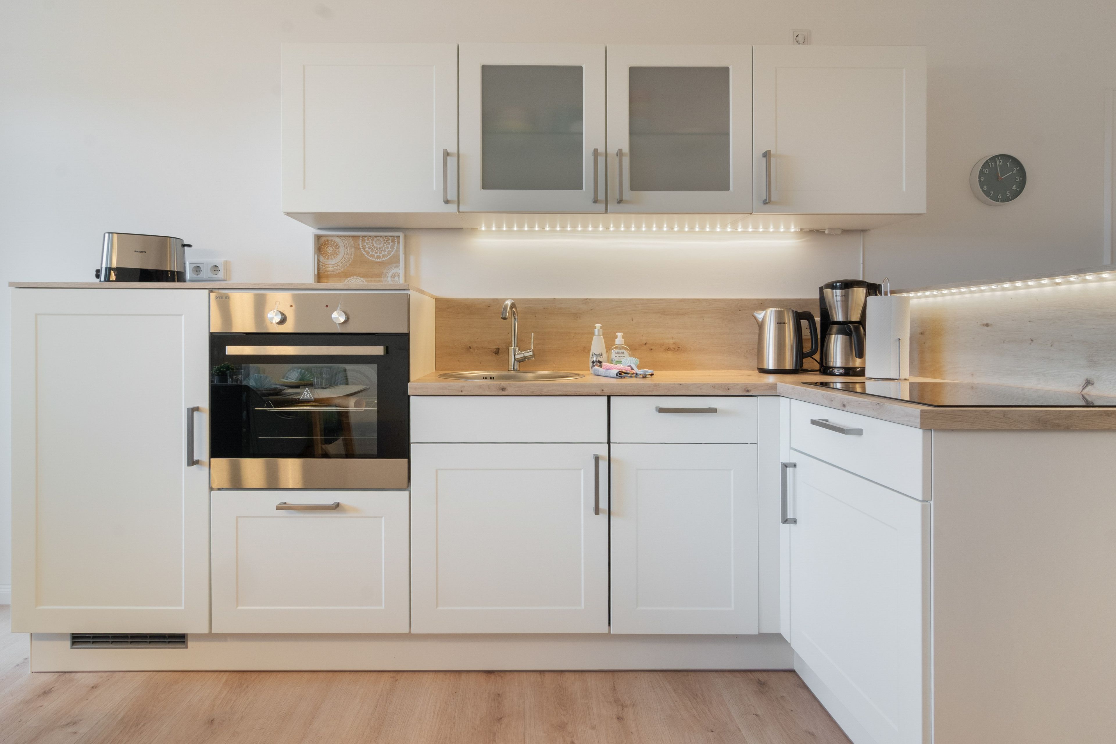 Eine moderne Küche mit weißen Schränken, Edelstahlgeräten und einer Holz Arbeitsplatte.