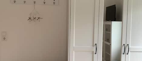 Una habitación con un banco gris, un armario blanco y un perchero con cuernos y un cartel que dice 'HOME'.