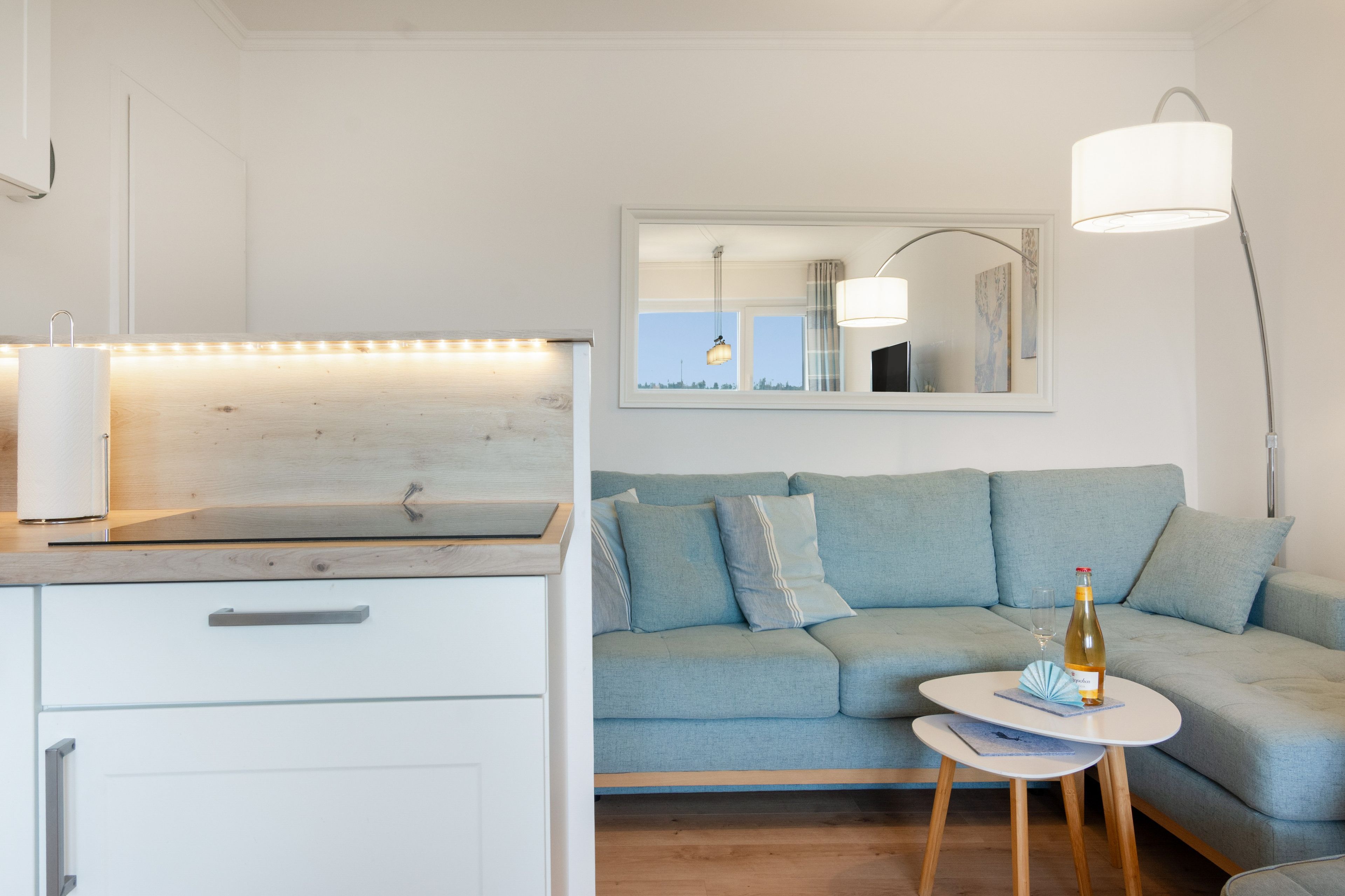 Ein modernes Wohnzimmer mit einer Couch, einem kleinen runden Tisch und einem Spiegel an der Wand.