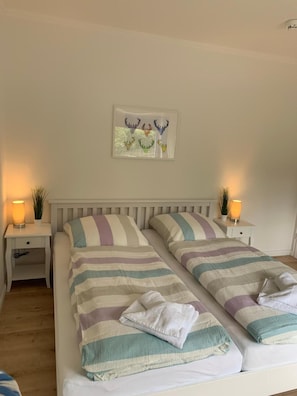 Ein Doppelbett mit gestreifter Bettwäsche, zwei Nachttische mit Lampen und ein Wandbild.