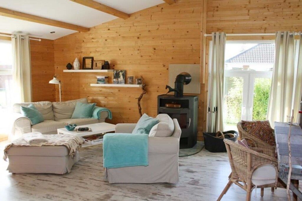 Un salon chaleureux avec une cheminée, un ensemble de canapés, une table basse et un fauteuil en osier.