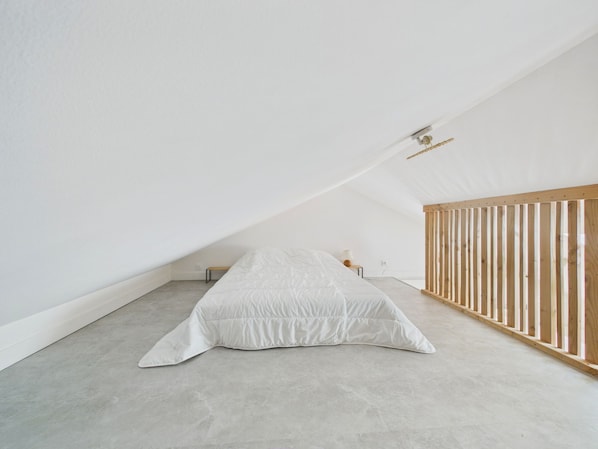 A minimalist room with a sloped ceiling, a single bed, a small bedside table, and a wooden crib. - House for 4, steps from the beach (La Plaine-sur-Mer)