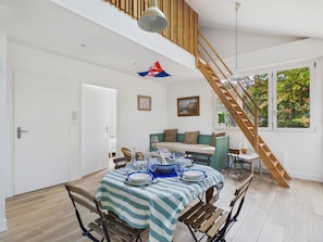 A dining area with a table set for four, a wooden staircase, and a view of trees through a window. - House for 4, steps from the beach (La Plaine-sur-Mer)