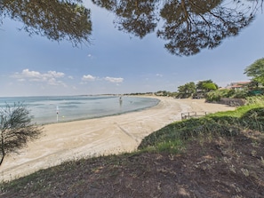 Ein Strand mit freiem Blick auf das Meer, einem Sandufer und einigen Bäumen.
