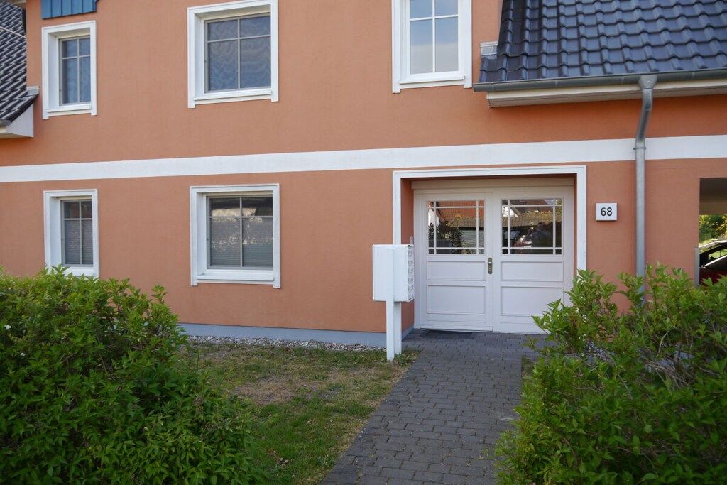 A residential building with a white door, windows, and a number '68' on the wall.
