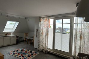 A kitchen with a dining area, a skylight, and a view through a sliding glass door. - Sünnenkringel Apt. 5 (Zingst)