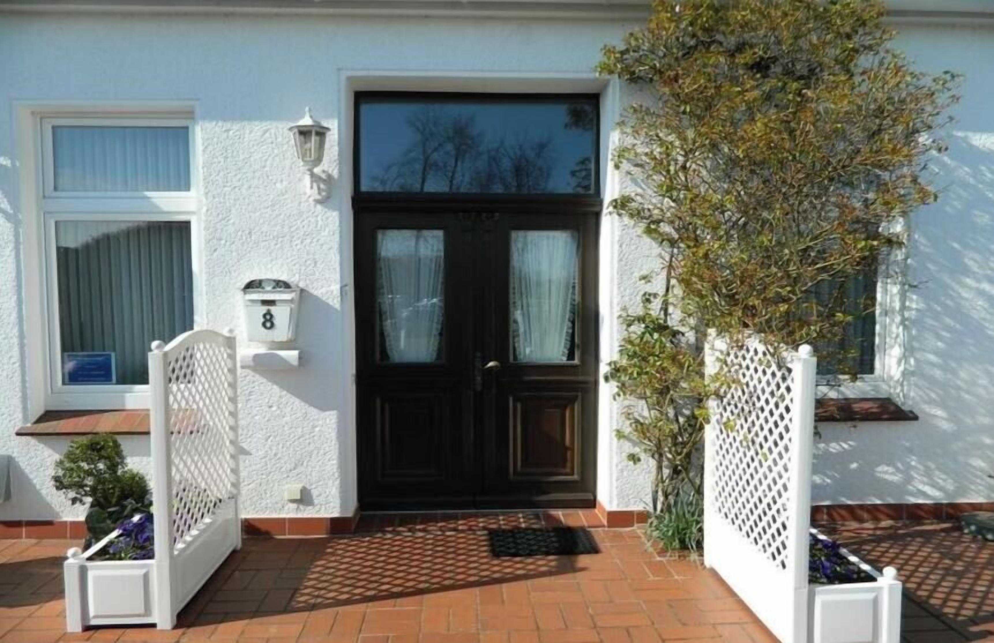 A house with a black front door, white walls, and a tiled entrance.