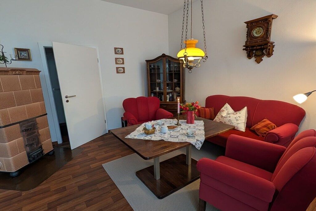 A living room with a red sofa, a wooden coffee table, and a hanging lamp.