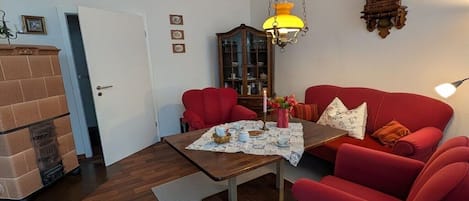 A living room with a red sofa, a wooden coffee table, and a hanging lamp.
