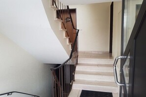 Un escalier avec une rampe métallique menant à un palier.
