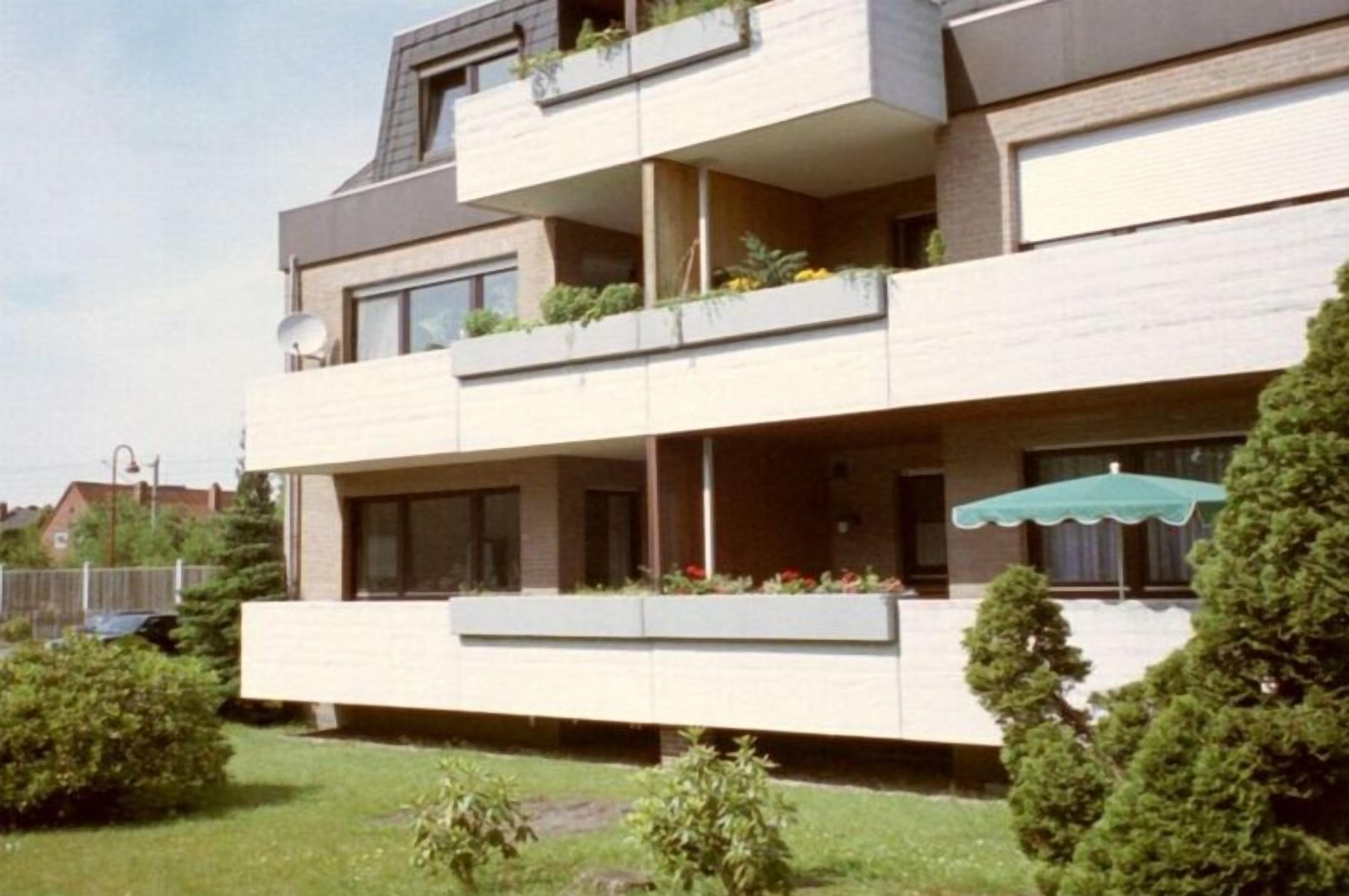 A modern multi-story building with balconies, large windows, and a flat roof.