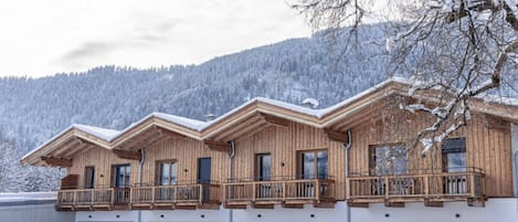 Una cabaña de madera de varios pisos con balcones, con una imponente montaña nevada de fondo.