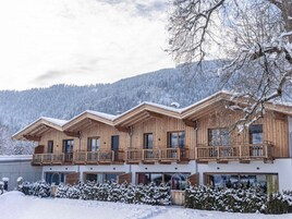 Una cabaña de madera de varios pisos con balcones, con una imponente montaña nevada de fondo.
